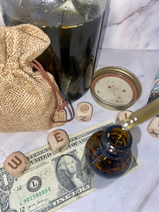 Bottle of money oil, spirit dice, money, and a small bag on a marble surface